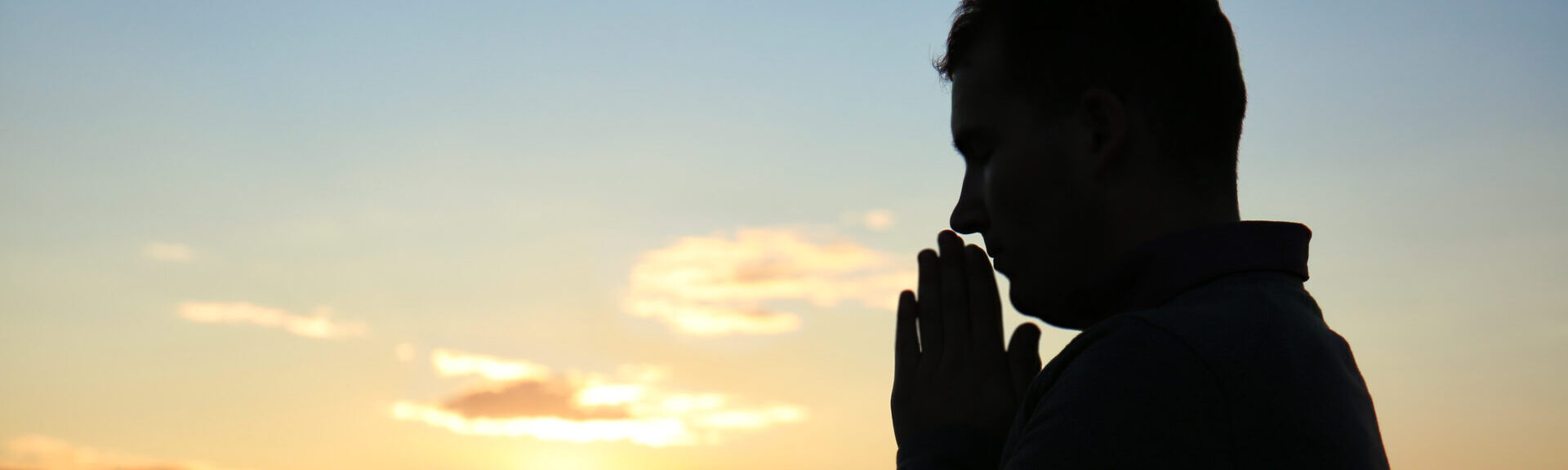 Religious Man Praying Outdoors At Sunset
